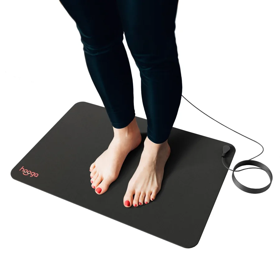 The Hooga carbon grounding mat in use, bare feet resting on it with the grounding cord attached